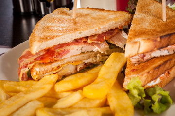 Clubsandwich auf getoastetem Weißbrot mit Speck und Pommes frit