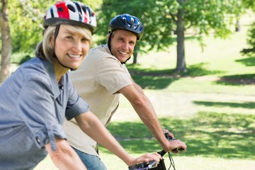 Naklejka premium Happy couple riding bicycles in park