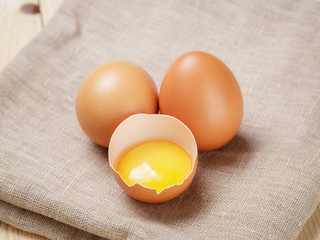 raw chicken eggs one open with yolk