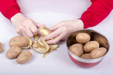 Alte Frau schält viele Kartoffel aus einem Kochtopf