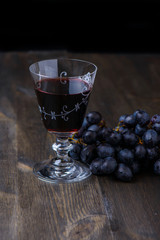 Red wine with grapes on the side on wood table