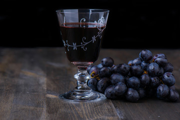 Red wine with grapes on the side on wood table
