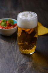 Beer with nachos and salsa in the background
