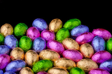 Chocolate Mini eggs wrapped in foil, black background