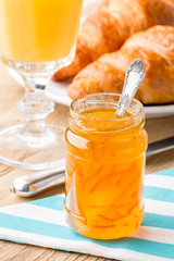 Orange jam with juice and croissants.  Shallow depth of field.