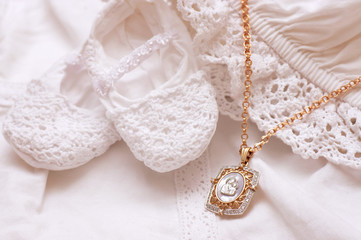 Baby shoes and white dress with golden icon for Christening