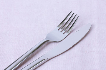 fork and knife on pink  napkin close up