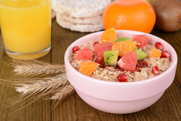 Delicious oatmeal with fruit in bowl on table close-up