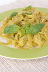 Delicious pasta with pesto on plate on table close-up