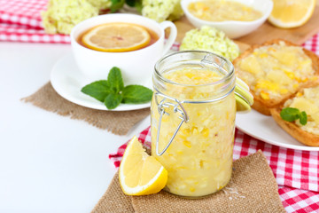Obraz na płótnie Canvas Tasty lemon jam with cup of tea on table close-up