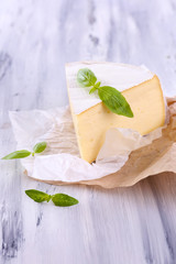 Tasty Camembert cheese with basil, on wooden table