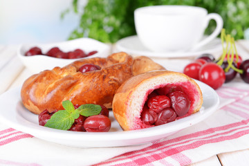 Fresh baked pasties with cherry on plate on table close-up