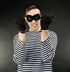 Thief with handcuffs on dark background