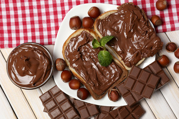 Bread with sweet chocolate hazelnut spread on wooden background