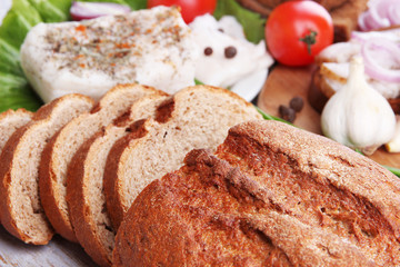 Slices of bread and lard with vegetables on table close up