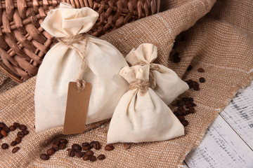 Sacks with coffee beans on wooden table, on sackcloth