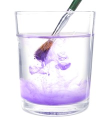 Brush with color paint in glass of water, isolated on white