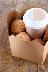 Hot coffee and cookies in box on wooden table close-up