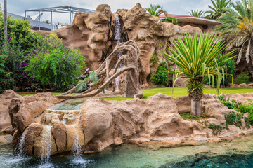Big animal enclosure in a zoo with a waterfall - obrazy, fototapety, plakaty