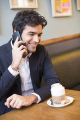 Handsome man calling with a cell phone in coffee bar