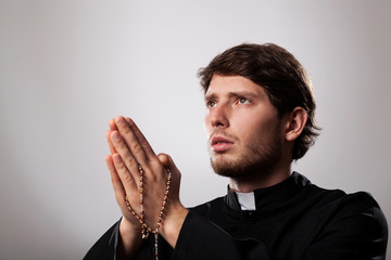 Priest with rosary - obrazy, fototapety, plakaty