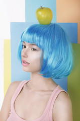 Imagination. Asian Woman in Blue Wig with Apple on her Head