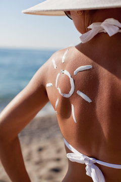 Tanning lotion in the shape of sun on woman's shoulder.