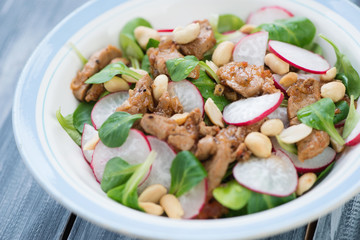 Salad with radish, roasted meat, corn salad leaves and peanuts