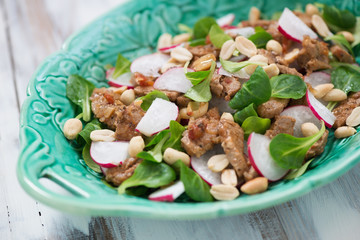 Salad with radish, roasted meat, corn salad leaves and peanuts