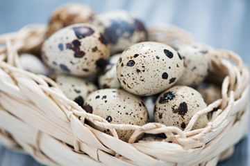 Naklejka na ściany i meble Close-up of raw quail eggs in a wicker basket