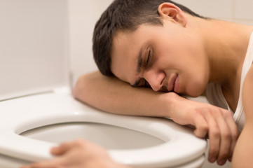 young man lying on toilet seat.