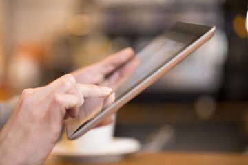 Close up of hands woman using her digital tablet in restaurant