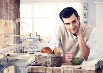 Handsome man having breakfast in cottage interior