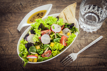 Leafy green mixed salad on a grunge wood table