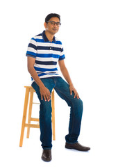 Fototapeta premium Full body indian man sitting on a chair over white background