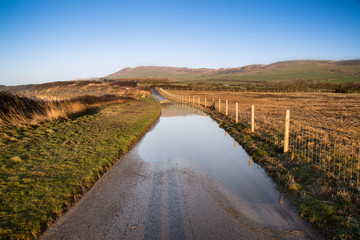 Fototapeta na wymiar Landscape image of flooded country lane in farm