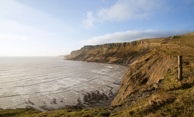 Beautiful coastal landscape at sunrise with cliffs and misty glo