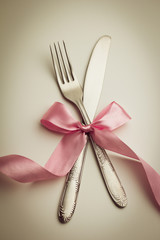 Fork and knife with decorative ribbon.