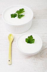 Two bowls topped with a parsley leaf and a spoon