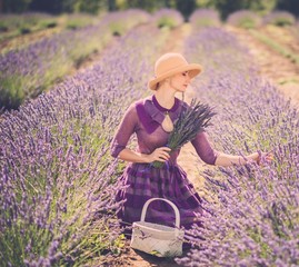 Woman in purple dress and hat with basket in lavender field