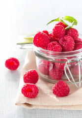Fresh raspberries in a jar on the table close-up.