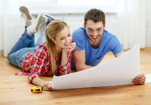 Smiling Couple Looking At Blueprint At Home