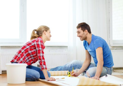 smiling couple measuring wallpaper