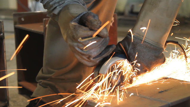 Industrial Worker cutting steel metal with grinder.