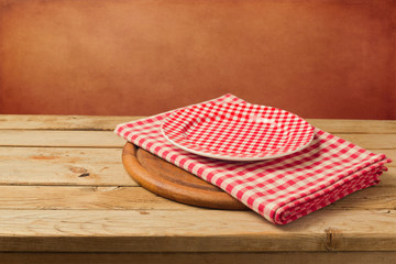 Empty checked plate and tablecloth on wooden table