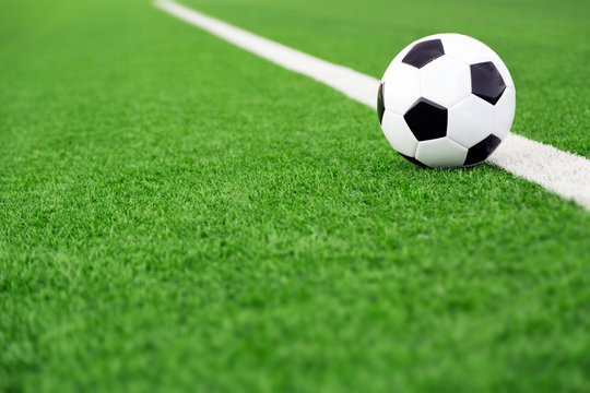 Traditional soccer ball on soccer field, green field sports background