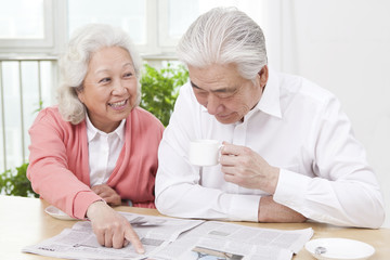 .Senior couple reading newspaper.