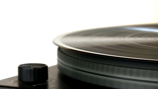 Close up of vinyl record spinning on turntable isolated on white