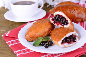Fresh baked pasties with currant on plate on table close-up