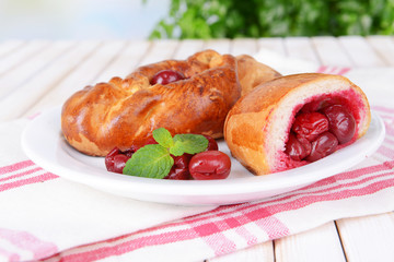 Fresh baked pasties with cherry on plate on table close-up